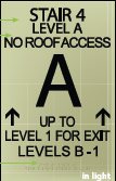 The same stairwell sign in daylight, its photoluminescent face a pale yellow